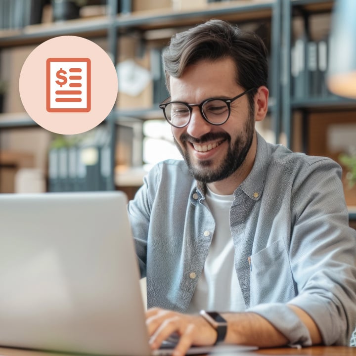 Happy young man smiling while browsing on his laptop in a library setting.