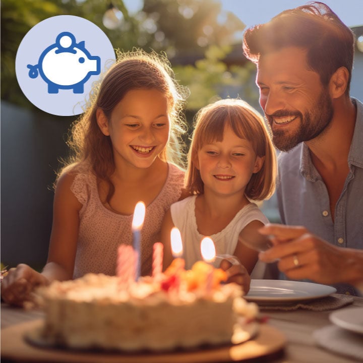 Father and two daughters about to blow out a birthday cake.