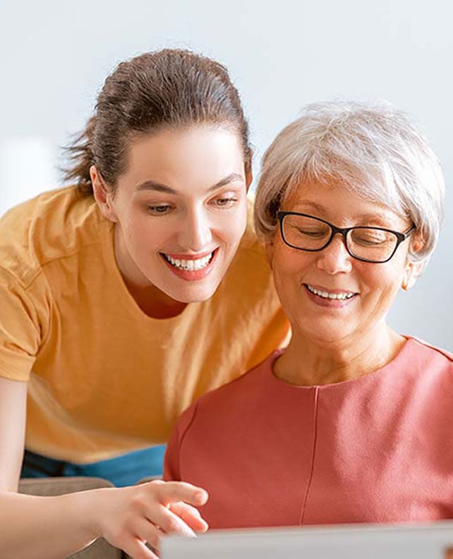 Younger woman and older woman smiling and looking at a tablet.